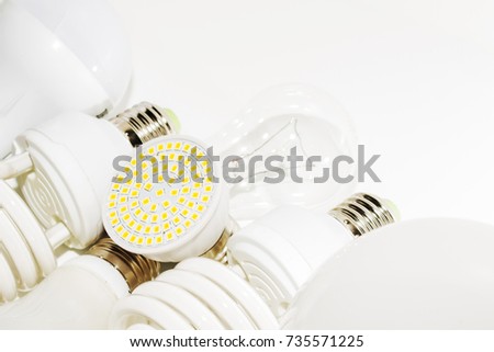 Several different led bulbs and compact fluorescent lamps with the size of the male screw base E27 on a light background
