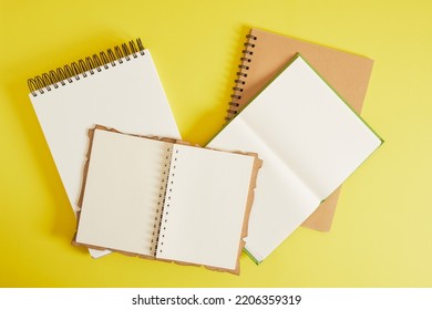 Several Different Notebooks For Sketching And Writing With Brown Craft Sheets On A Yellow Background, A Notebook With Aspiral And Binding, Mockup Top View