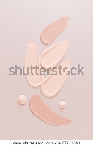 Several different samples of liquid foundation powder on a beige background with drops of foundation. Top Vertical view. Product presentation. layout