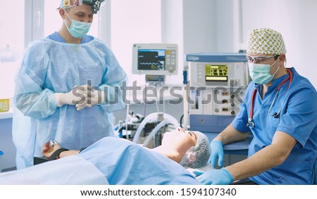 Several doctors surrounding patient on operation table during t