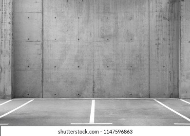 Several empty parking lots in an open garage with concrete wall