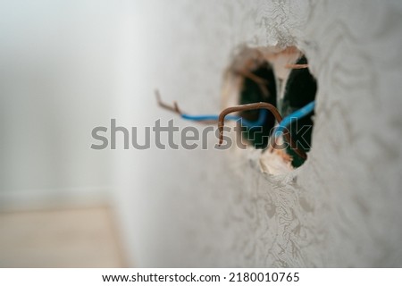 Several exposed electrical copper wires protruding from a whitewall. electrical wires and connector installed in plasterboard drywall for gypsum walls in apartment is under construction and remodeling