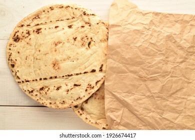 Several Freshly Baked Pita Bread In A Paper Bag, Close-up, On A Wooden Table, Top View.