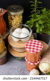 Several Glass Containers Piled Full Of Homemade Meal, Tomato Sauce, Eggs, Quinoa, Pasta, Etc... Over A Cement-like Table.