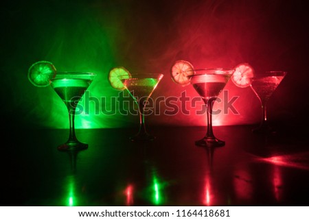 Several glasses of famous cocktail Martini, shot at a bar with dark toned foggy background and disco lights. Club drink concept. Selective focus