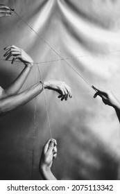 Several hands joined and connected through a taut thread. Black 
