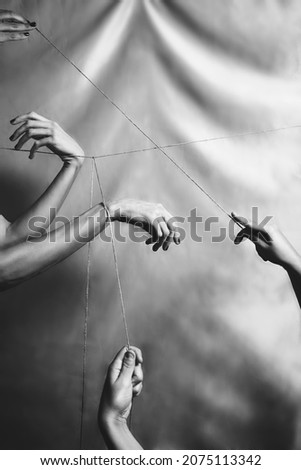 Several hands joined and connected through a taut thread. Black 