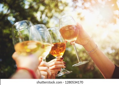 Several Hands Raise Glasses Of Wine To The Sky, Against The Background Of Green Trees, Toast, Making Cheers