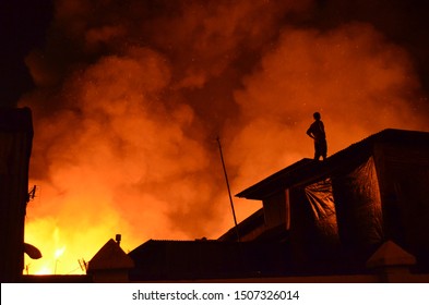 Several Houses Caught Fire, Man Standing On The Roof Of The House. Feel So Sad And Panic See The Fire Gets Bigger Burning Their House.