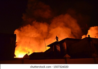 Several Houses Caught Fire, Man Standing On The Roof Of The House. Feel So Sad And Panic See The Fire Gets Bigger Burning Their House.