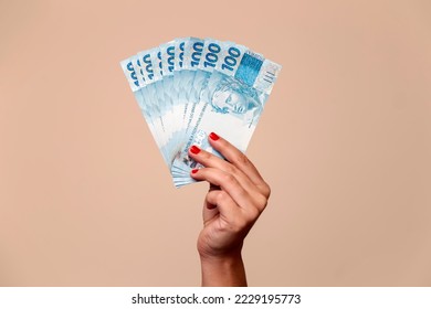 several hundred real bills - money from Brazil in a womans hand with red nails - Shutterstock ID 2229195773