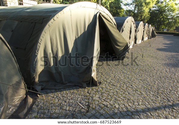 several large military tents on the paved area as a\
camp for youth