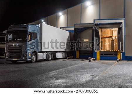 Several loading docks with trucks backed up and an open dock door showing palletized goods