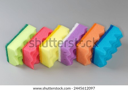Several multi colored kitchen soft synthetic cleaning sponges with hard urethane abrasive layer on a gray background
