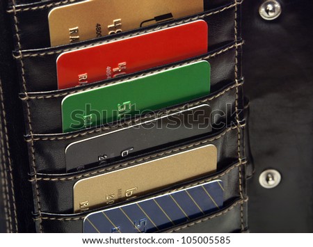 Several Multicolored  red green black  blue gold credit cards in the black wallet.