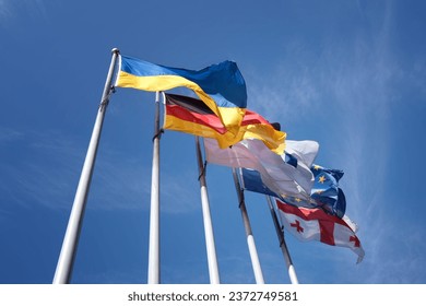 Several national flags flutter in the wind, mounted on a steel flagpole. Ukraine, Germany, European Union, Georgia.