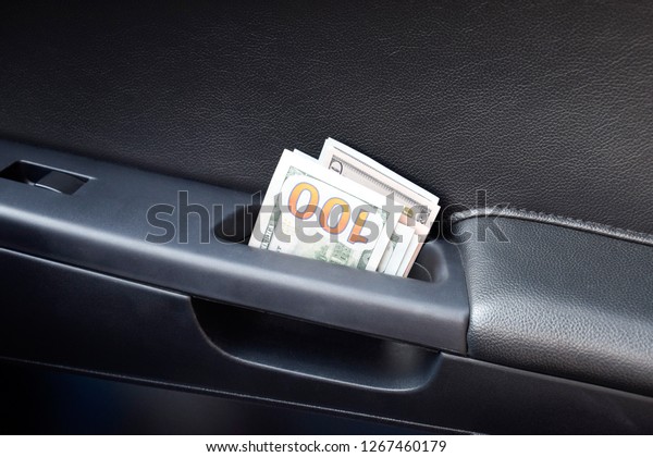 Several notes of US\
dollars and are folded in half in the door handle of the car. The\
money in the car.