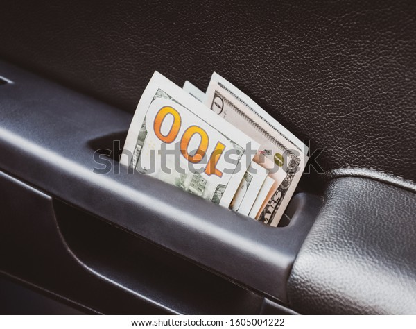 Several notes of US\
dollars and are folded in half in the door handle of the car. The\
money in the car.
