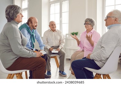 Several old people in group therapy at the retirement home. Senior men and women sitting in a circle, talking about their lives, sharing thoughts and ideas, and taking notes in paper notebooks - Powered by Shutterstock