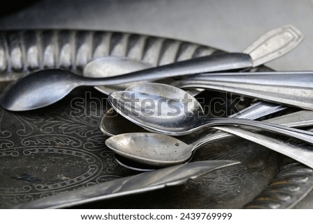 Several old silver spoons on a shiny, antique tray.