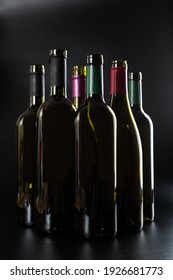 several open Bottles of wine are in a row on a dark glossy background.