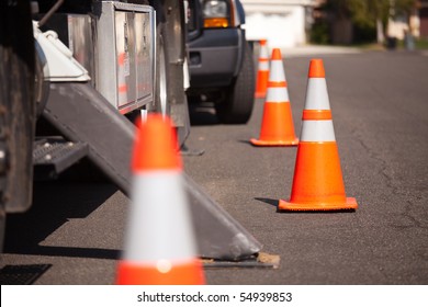 Several Orange Hazard Cones And Utility Truck In Street.