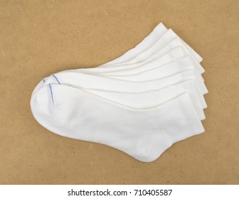 Several Pairs Of Diabetic Socks On A Brown Pressed Board.