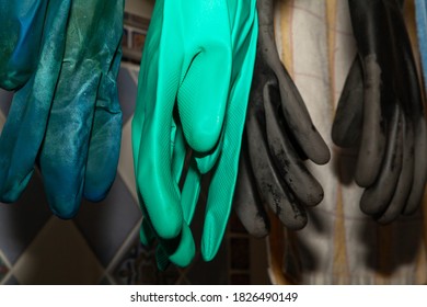 Several Pairs Of Rubber Gloves Of Different Colors Hang Vertically Close-up

