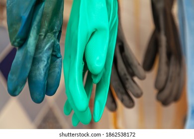 Several Pairs Of Rubber Gloves Of Different Colors Hang Vertically Close-up

