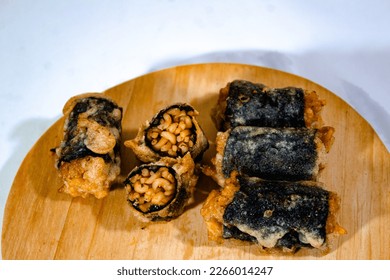 several pieces of fried samyang wrapped in nori skin arranged on a wooden cutting board with a plain white background