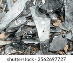 Several piles of scattered glass shards are spread across the ground, reflecting light with their sharp edges and varied sizes, creating a messy and dangerous sight.