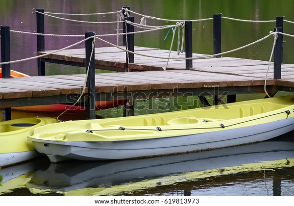 Several plastic canoes floating on water and moored\
with rope