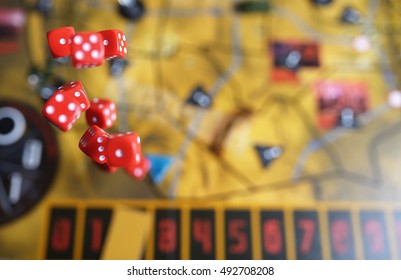 Several Rolling Red Dice Fall On A Table With Boardgame. Gameplay Moments