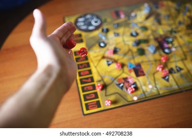 Several Rolling Red Dice Fall On A Table With Boardgame. Gameplay Moments