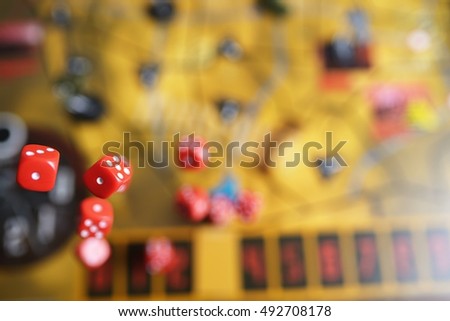 Several rolling red dice fall on a table with boardgame. Gameplay moments