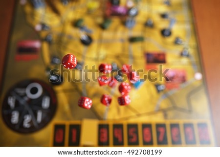 Several rolling red dice fall on a table with boardgame. Gameplay moments