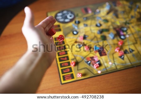 Several rolling red dice fall on a table with boardgame. Gameplay moments