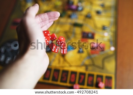 Several rolling red dice fall on a table with boardgame. Gameplay moments