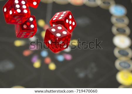 Several rolling red dice fall on a table with boardgame. Gameplay moments.