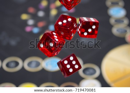 Several rolling red dice fall on a table with boardgame. Gameplay moments.