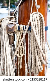 Several ropes hang from the iron fittings of a mast of a sailing ship.