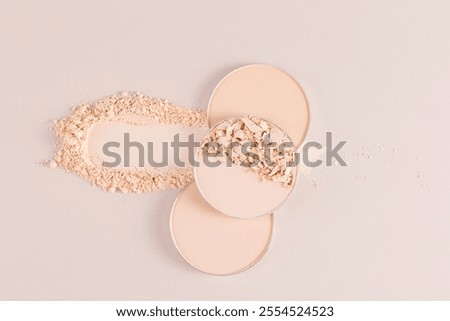 Several round blocks, a refill of compact powder in natural shades lie on a beautiful sample of loose powder. top view. cosmetic texture