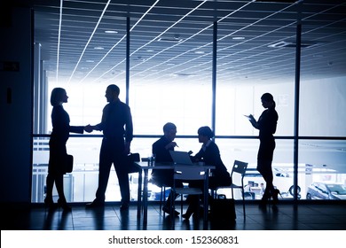 Several silhouettes of businesspeople interacting  background business centrer