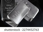 Several silver bars of various weights on a dark background. 