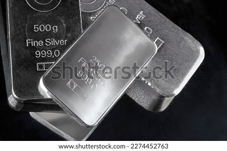 Several silver bars of various weights on a dark background. 