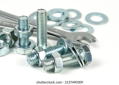 Several silver metal fixing bolts on a white background.Metal bolts and nuts. Wrenches for working with bolts and nuts. Close-up