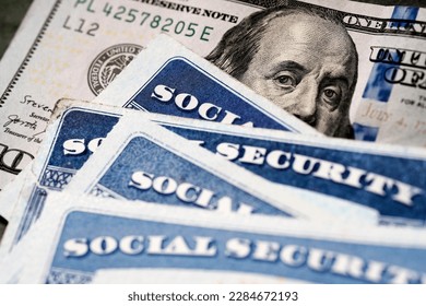 Several Social Security Cards on a US United States one hundred dollar bill $100 system of benefits for retired elderly people - Shutterstock ID 2284672193