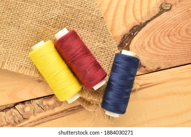 Several spools of colored thread, close-up, on a wooden table, top view.