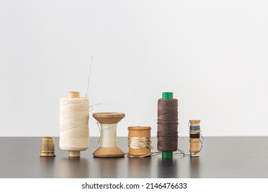 Several spools of cotton and silk thread, needle and thimble. Horizontal with space for your logo or text