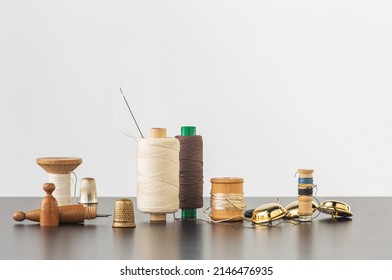Several spools of cotton thread, needle, buttons and thimbles. Horizontal with space for your logo or text